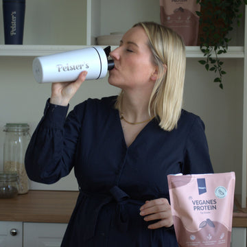 Frau die aus einem Edelstahlshaker veganes Bio Proteinpulver trinkt 