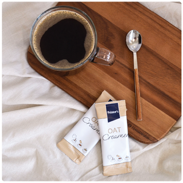 Oat Creamer Sticks auf einem Brett neben schwarzem Kaffee