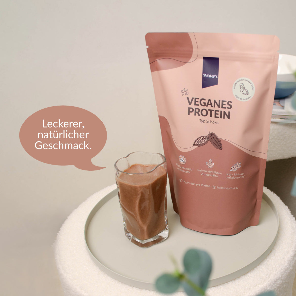 Volles Glas mit Veganem Schoko Proteinshake und einer Sprechblase "Leckerer, natürlicher Geschmack"